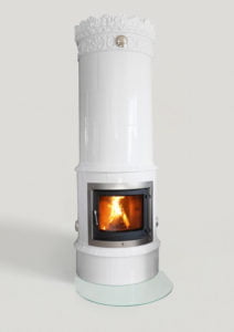 Vit kakelugn med brinnande eld inuti, dekorerad med ornament upptill och placerad på golvskydd av glas.