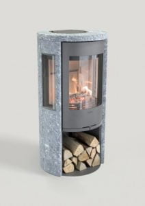 Modern kamin i grå sten med glaslucka, synliga lågor och vedförvaring under. Perfekt för inomhusuppvärmning och stilfull inredning.