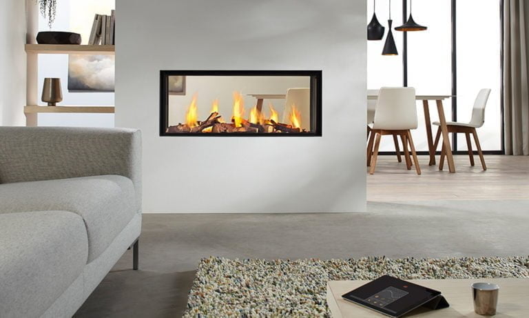 Modernt vardagsrum med stilren inbyggd eldstad i väggen, grå soffa, matbord och hängande lampor. Mysig atmosfär med inredning i ljusa toner.