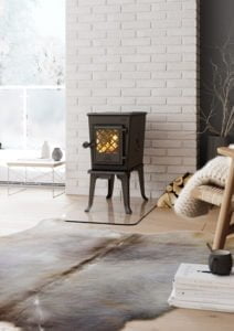 Vedeldad kamin i ett modernt vardagsrum med vit tegelvägg, pälsmatta och vedförvaring. Mysig inredning med vinterutsikt genom fönstret. Nyckelord: kamin, vardagsrum.