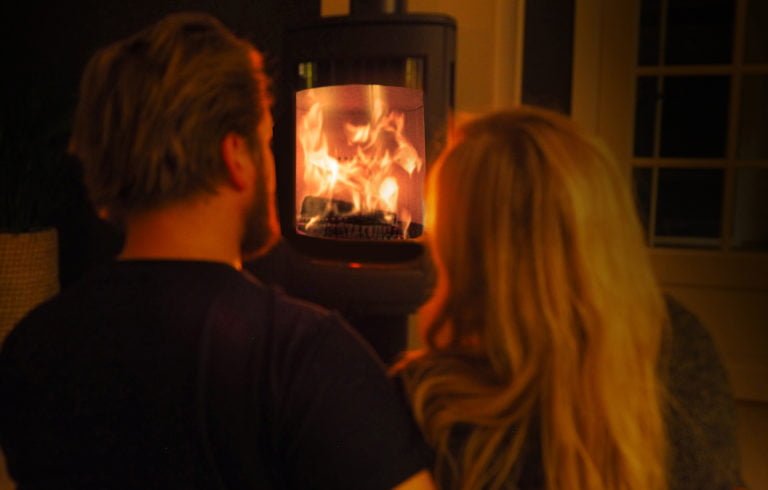 Par ser på eldstad med brinnande lågor, vilket skapar en varm och mysig atmosfär.