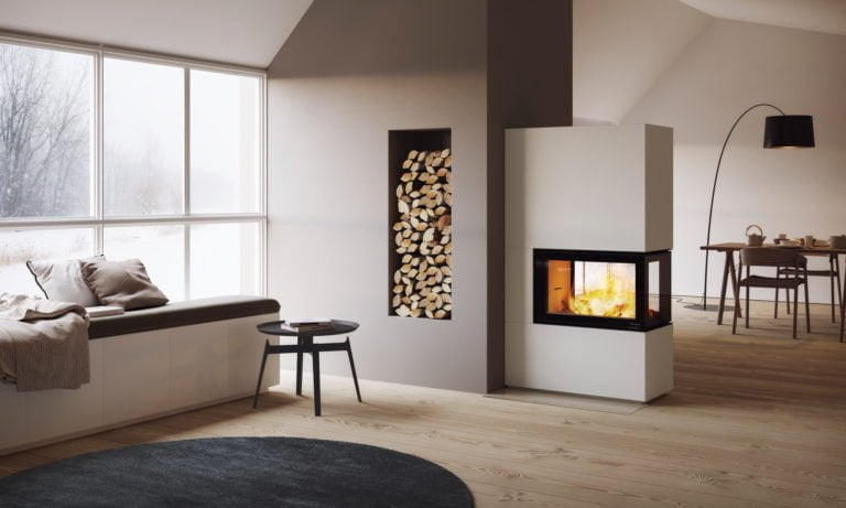 Modern vardagsrumsinteriör med stor fönster, braskamin och vedförvaring. Mysig sittplats vid fönstret, träbord och stolar i bakgrunden. Ljus och stilren design.