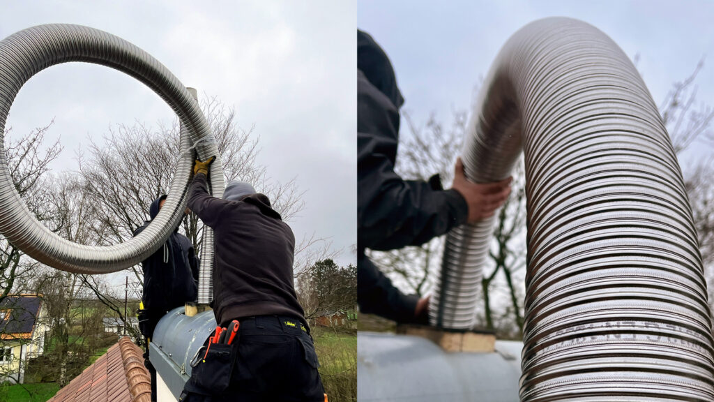 Två personer installerar en flexibel metallskorsten på ett hustak. Skorstenen är stor och böjd, och omgivningen visar träd och hus.